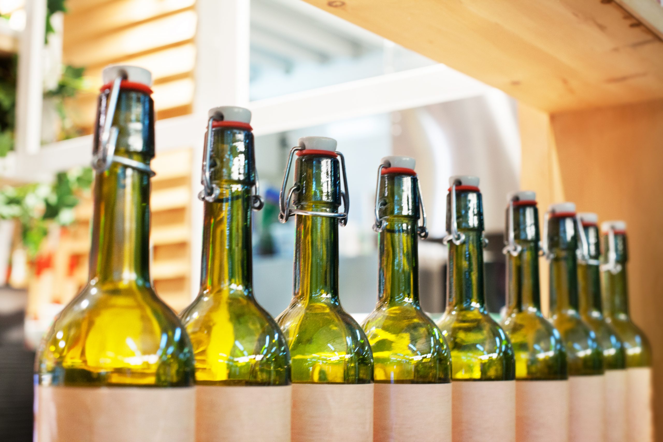 Green,Glass,Bottles,Of,Wine,In,Line,On,Wood,Shelf,